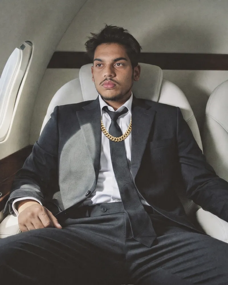 Ansh Gupta, custom jeweler in Bangkok, wearing a gold Cuban chain and emerald bracelet